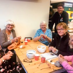 Strikker. Foto Roy Myrland "Dra'te Hæljeroa" og Søndersrødtunet, -stedet hvor folk møtes. -Der det er strikke-cafe hver onsdag kveld og praten går både løst og ledig. Det gjør strikkepinnene også.  Strikkecafeen har holdt på i flere år på Søndersrødtunet. Kjøpmann Dag Arild Bakken forteller til nettavisa Langsveien.no: Dette er noe av det viktigste jeg legger til rette for i og rundt butikken. Det at folk møtes og kan prate om stort og smått, ha det hyggelig og samtidig inkludere og bidra til at samfunnet vårt her på "solkysten" lengst sør i Vestfold blir enda litt bedre, er det viktig og gruelig moro å være med på. På bildet over fra venstre: Lillian Tvetene, som strikke Marius genser til sin sønn Jens Martin. Toril Brathagen jobber med moteriktig strikketøy. Det skal bli sommergenser i årets sommerfarger forteller hun. Gunbjørg Wirgenes strikke bunadsjakke til barn, men er også opptatt av bunader. Valdres folkemuseum sin bunadssamling er et sted hun kunne tenkt seg og vært en tur. Catharina Darre strikker kofte. Det er Vilde som skal få genseren Laila Aske Johansen så fint strikker-. Avdelingsleder Thomas Berntzen er "hanen i kørja" denne kvelden og sørger for de strikkelgade jentene får både litt ekstra oppmerksomhet og gratis kaffe når de møtes.