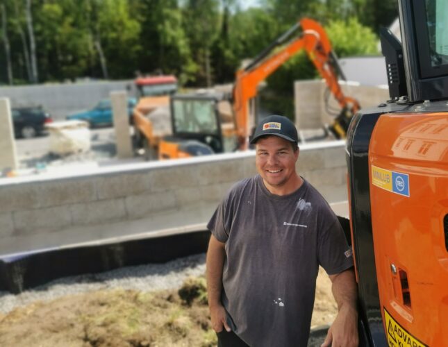 Dyktig og nøyaktig fagmann med gravemaskin, traktor og tilhenger.