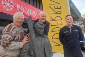 Ridderrennet får ny arena Sundag 30. mars startar årets Ridderuke på Beitostølen, og kulminerer med det tradisjonsrike Ridderrennet laurdag 5. april. Arrangementet samlar kvart år deltakarar med funksjonsnedsetjingar frå heile verda til ei veke fylt med idrettsglede, meistring og fellesskap. Biletet over: Desse karane, som står ved statuen av legendariske Steinar Hovi, kan du høyre i podkasten siste nytt og planar for årets Ridderuke og Ridderrenn. Frå venstre: redaktør for Langs Vegen No, Roy Myrland, styreleiar Tom Bratlie og generalsekretær Martin Feiring Sletten i Foreningen Ridderrennet. I år blir det ei lita, men viktig endring: Ridderrennet vert flytta frå dei flate myrene ved Beitostølen Helsesportsenter, som vanlegvis er arena for løpet. Trass i stor innsats for å halde løypenettet opent og i god stand, har snøsmelting og vårvêr gjort det umogleg å arrangere rennet der som planlagt. Løysinga er heldigvis nær: Beitostølen skistadion – berre nokre hundre meter unna – opnar sitt løypenett for Ridderrennet. Stadionsjef Kjell B. Melbybråten, i samarbeid med Viljar Aasan frå Helsesportsenteret – ein av landets fremste ekspertar på sportsutstyr for funksjonshemma – samt andre gode hjelperar, har tilrettelagt to løyper på 1,5 og 2 kilometer. Desse er spesielt utforma med doserte svingar og godt snøunderlag, slik at både ståande og sittande utøvarar trygt kan delta. I desse løypene har også "Team Pølsa", med Øystein Pettersen i spissen, trena og førebudd seg til VM – noko som gjev ei ekstra stasleg ramme rundt årets Ridderrenn. Generalsekretær for Ridderrennet, Martin Feiring Sletten, seier til langsvegen.no at flyttinga har gått heilt smertefritt, takka vere ein erfaren og dedikert frivilligstab. – Dette er 61. gongen Ridderrennet vert arrangert, og med så mykje erfaring i organisasjonen, har årets utfordringar blitt løyste på imponerande vis. Vi er sikre på at årets renn blir ei positiv og minneverdig oppleving for alle som deltek, seier Sletten – og legg til: – Det er jo litt stas å få konkurrere i dei same løypene som både Johaug, Klæbo og verdseliten – og no også Team Pølsa – har brukt. No er alt klart for ei ny veke fylt med meistring, idrettsglede og gode opplevingar i Valdres – Ridderuka 2025 er i gang!